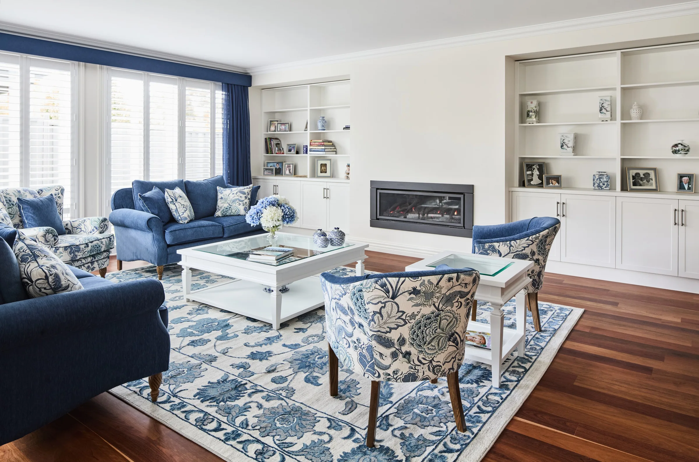 Living room at Thom St with navy sofas, built-in white joinery and a gas fireplace