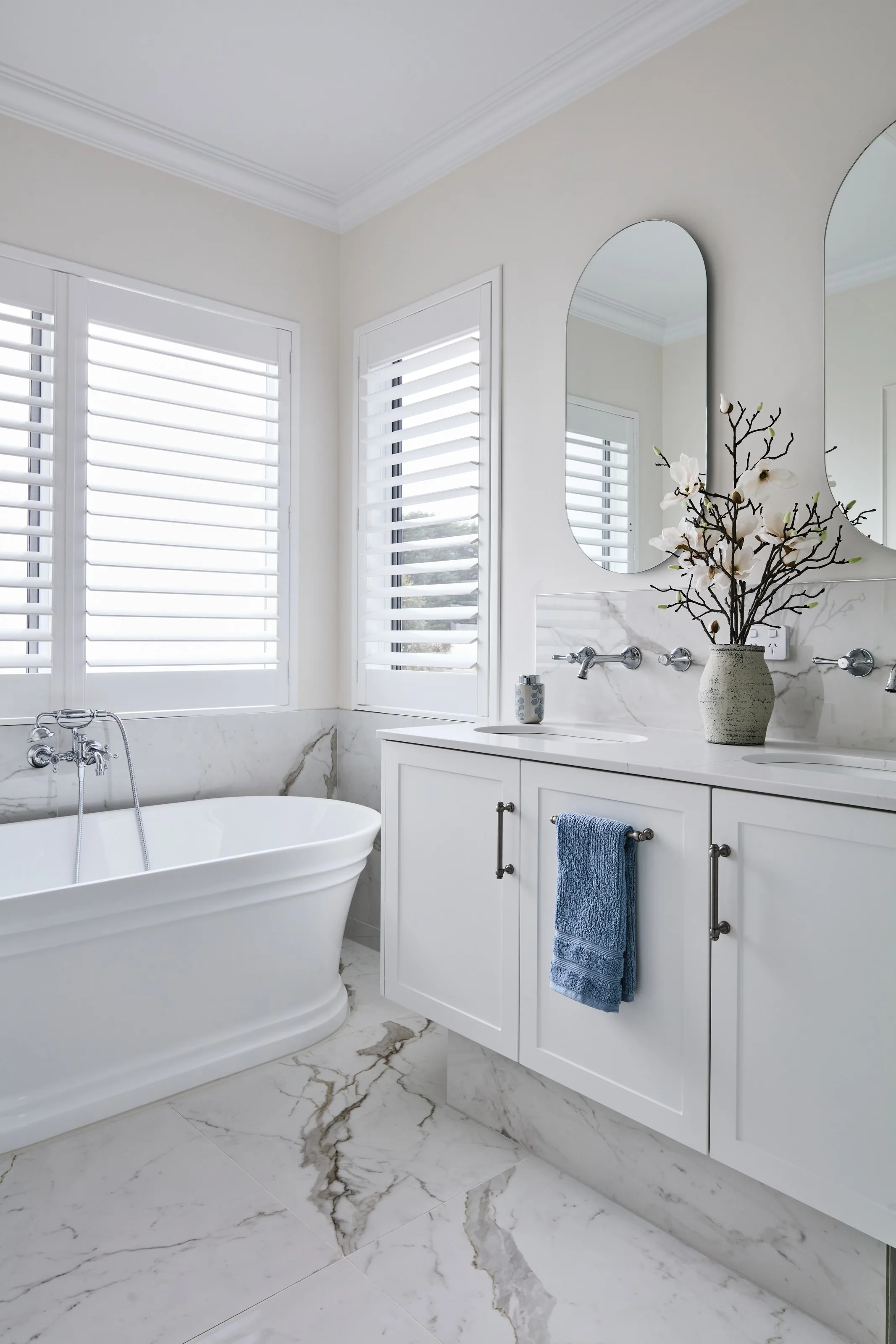 Ensuite vanity with twin basins, wall-mounted tapware and marble-look floor tiles beside the bath