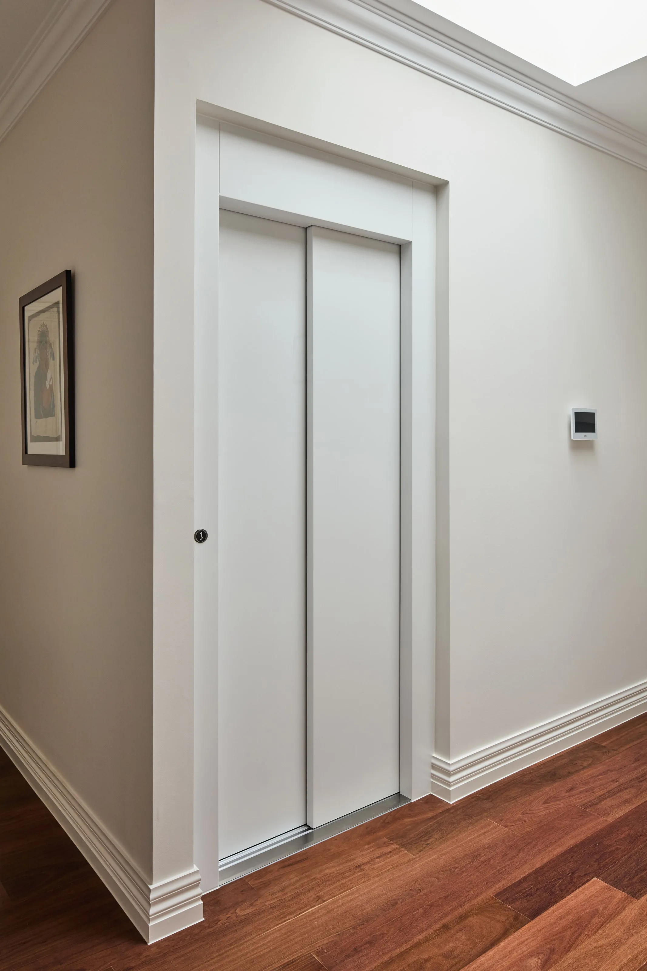 Lift doors closed flush into the hallway wall, deep skirting and cornice either side