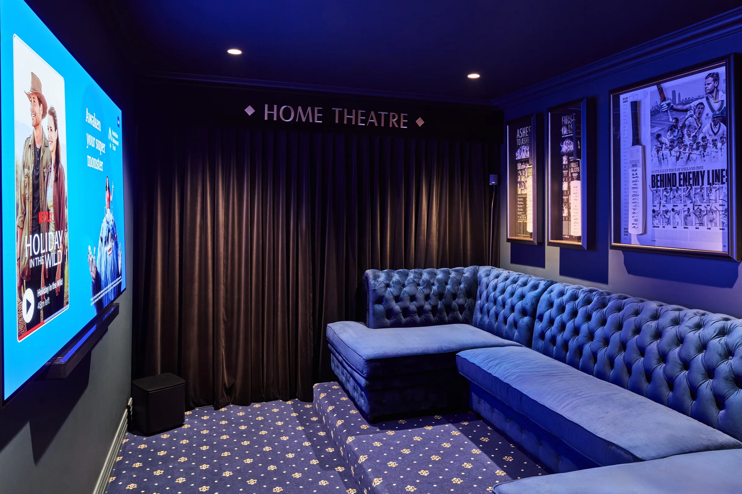 Home theatre at Thom St with a tufted blue velvet lounge, screen and patterned carpet