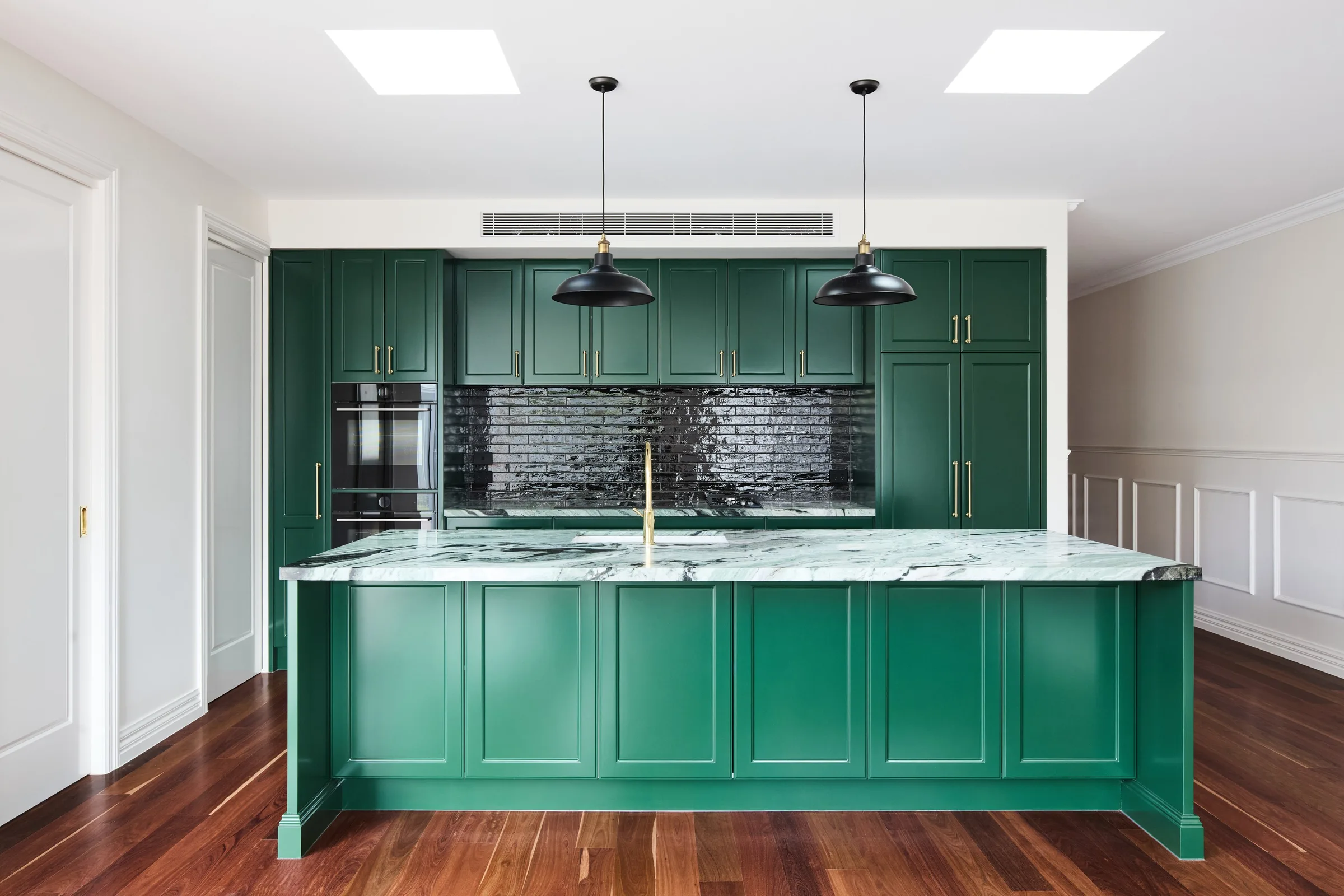 Kitchen of the second home at Thom St, deep green shaker joinery with a black brick splashback and pendant lights