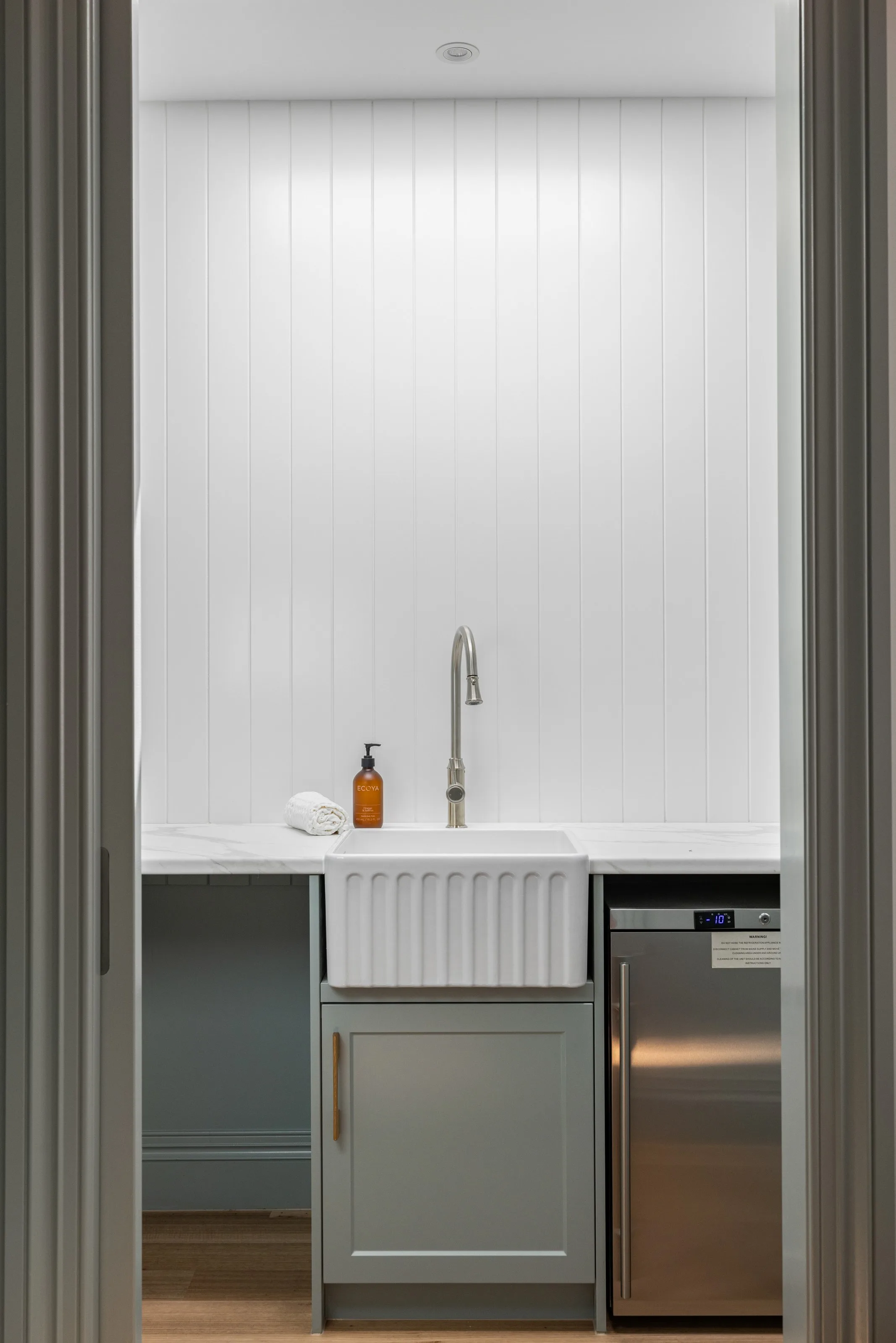 Butler&rsquo;s pantry through the doorway &mdash; fluted apron sink, stone benchtop and white VJ panelling
