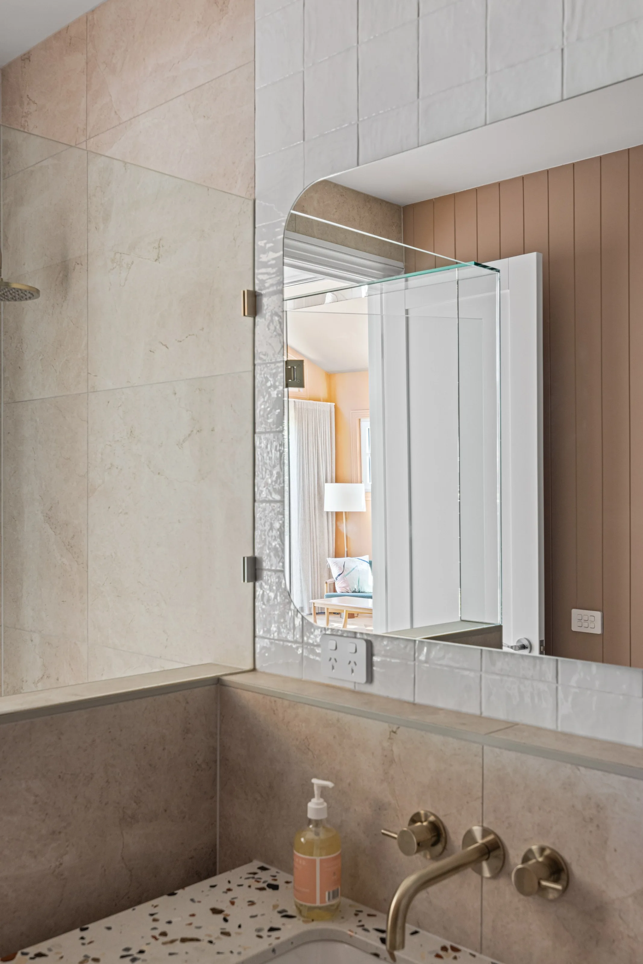 Mirrored cabinet reflecting the bedroom, stone-look tiles and brushed tapware over terrazzo