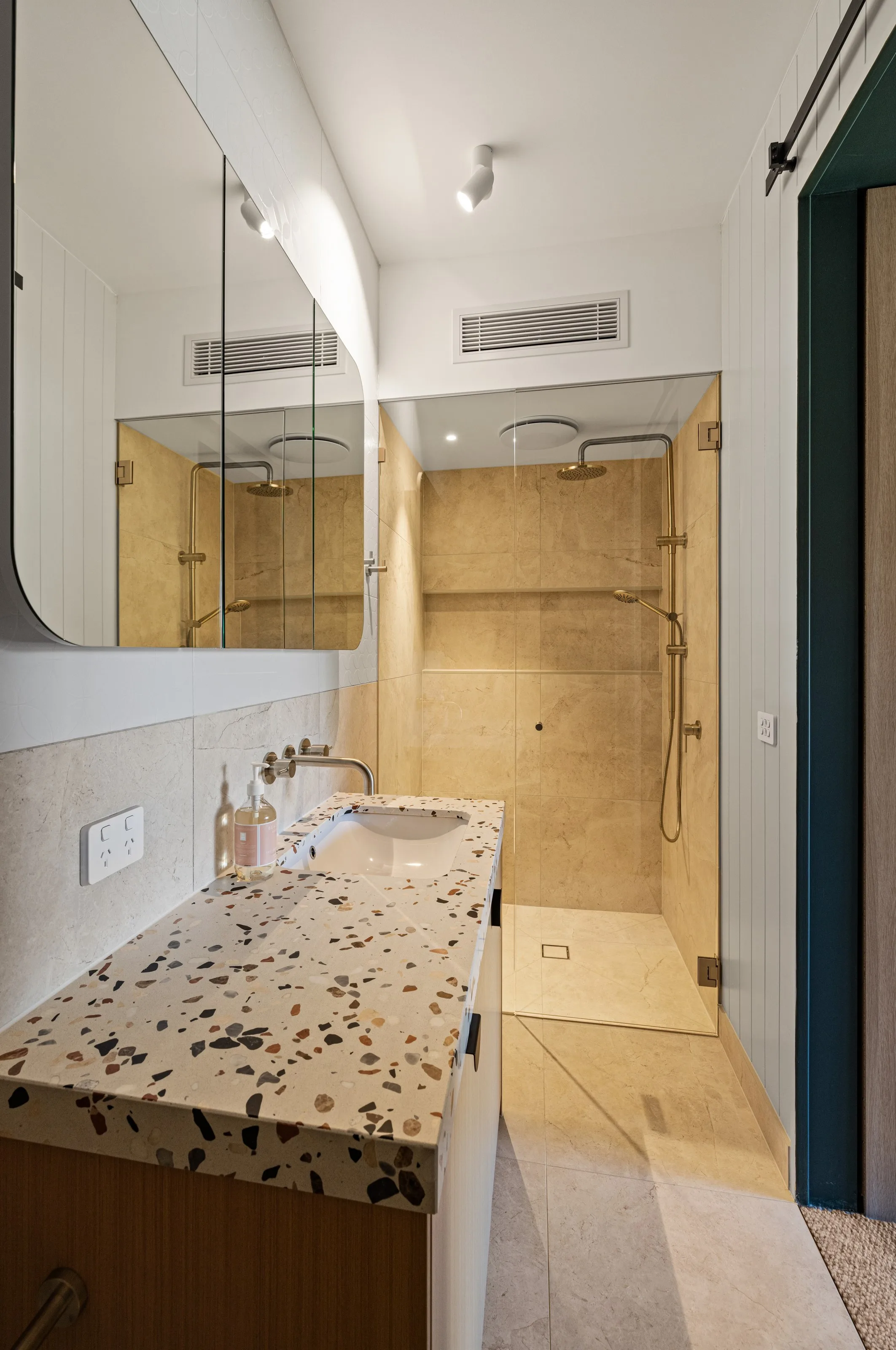 Ensuite with a terrazzo-topped timber vanity, mirrored shaving cabinet and walk-in shower in warm stone tiles