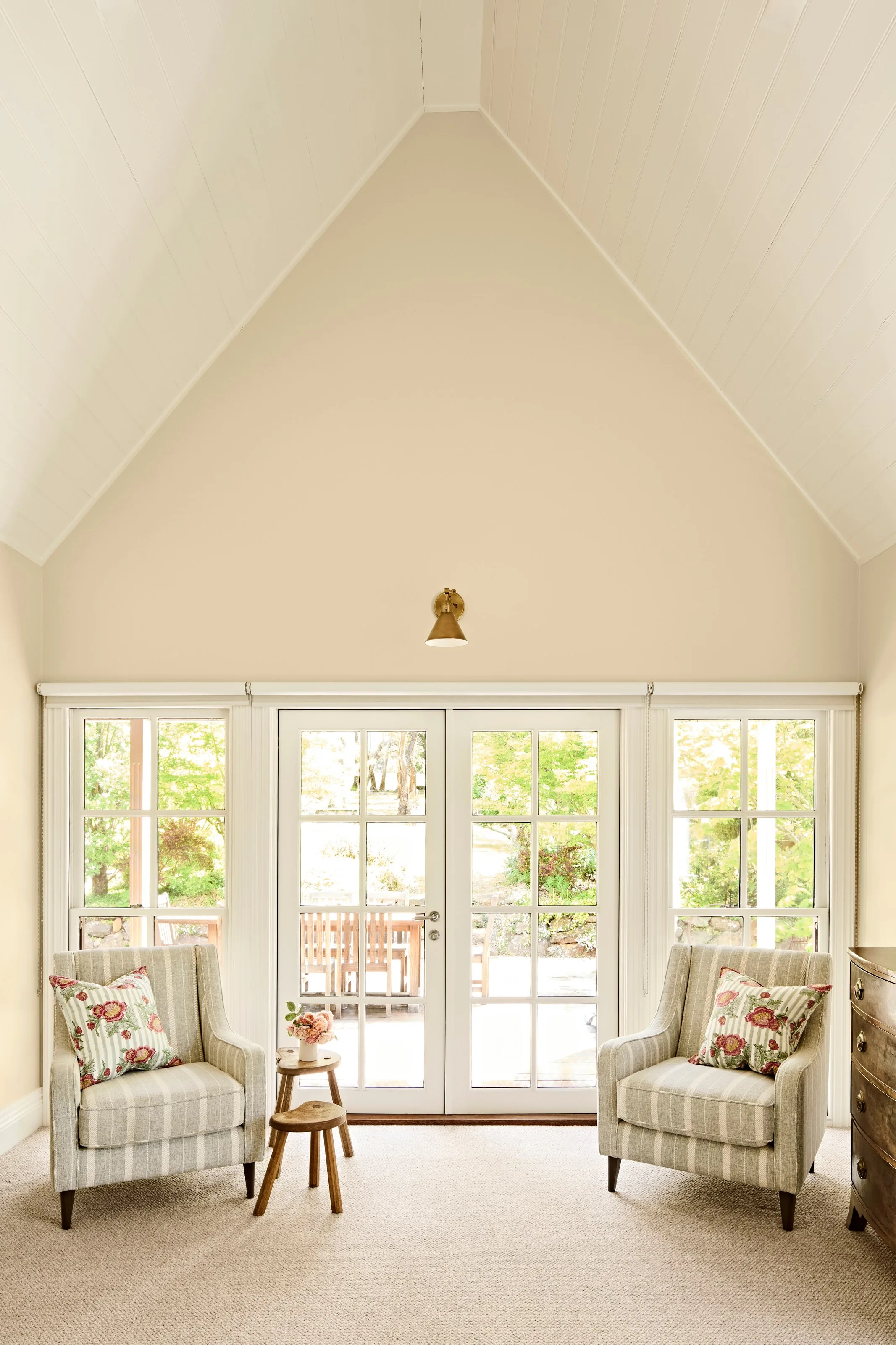 Cathedral ceiling above French doors to the deck, flanked by striped armchairs