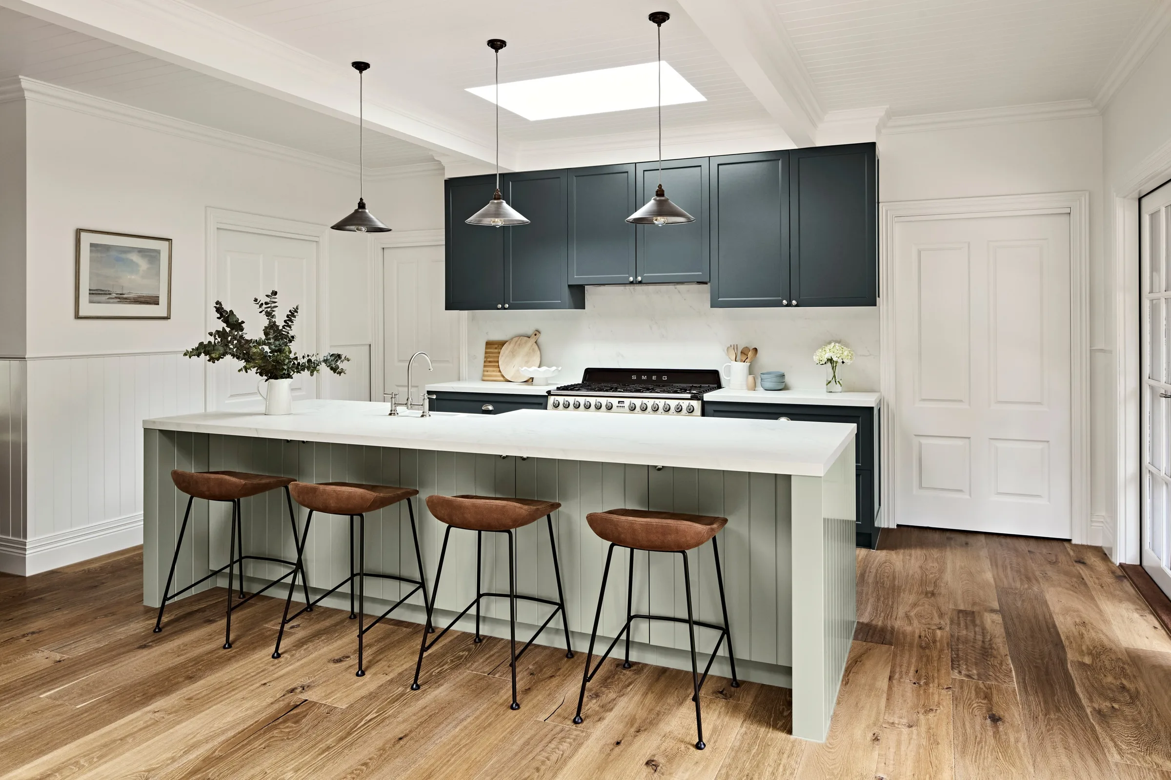 Wide view of the kitchen, charcoal overhead joinery above a white stone benchtop