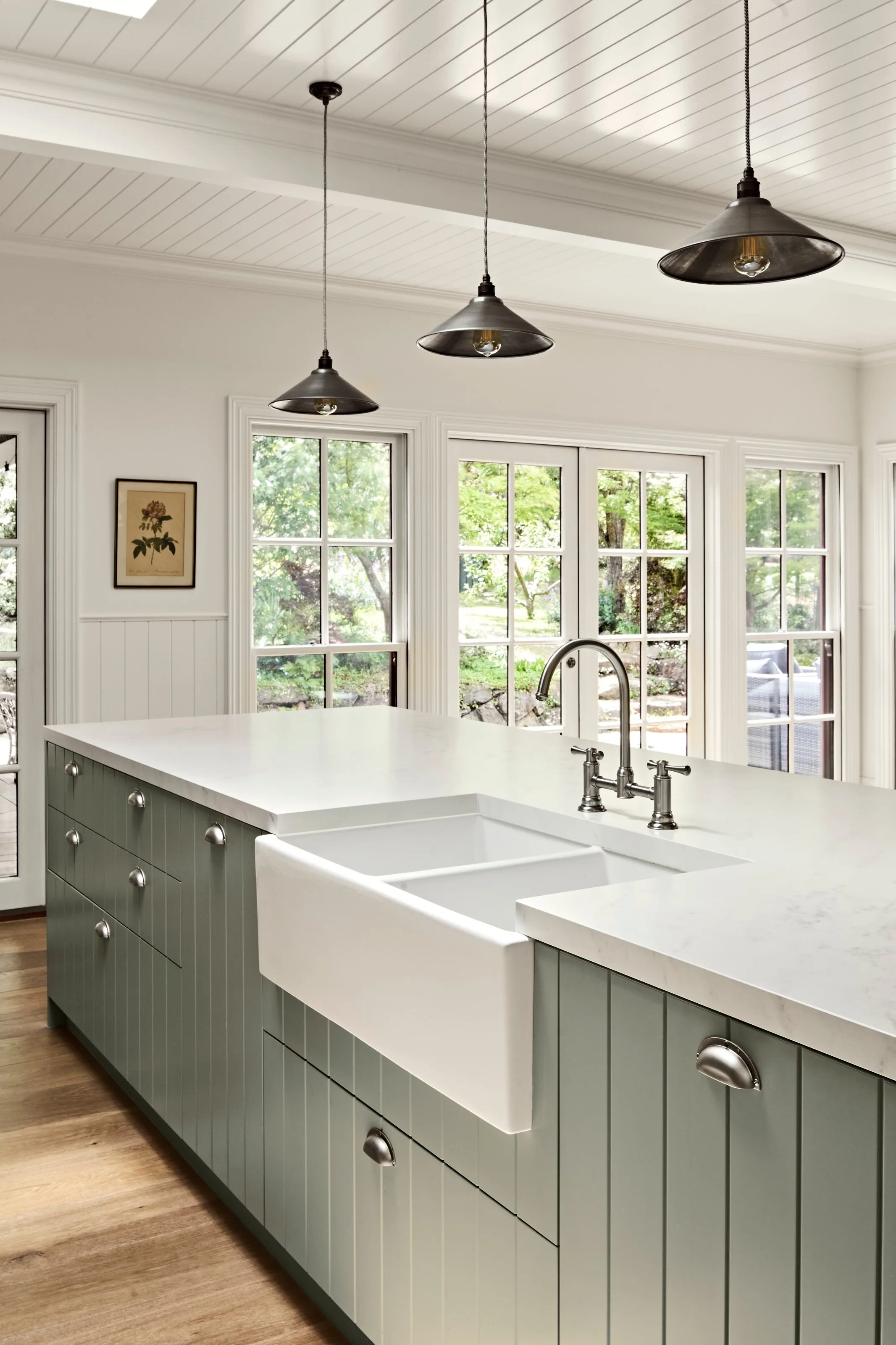 Apron-front butler sink and bridge tapware set into the sage green island
