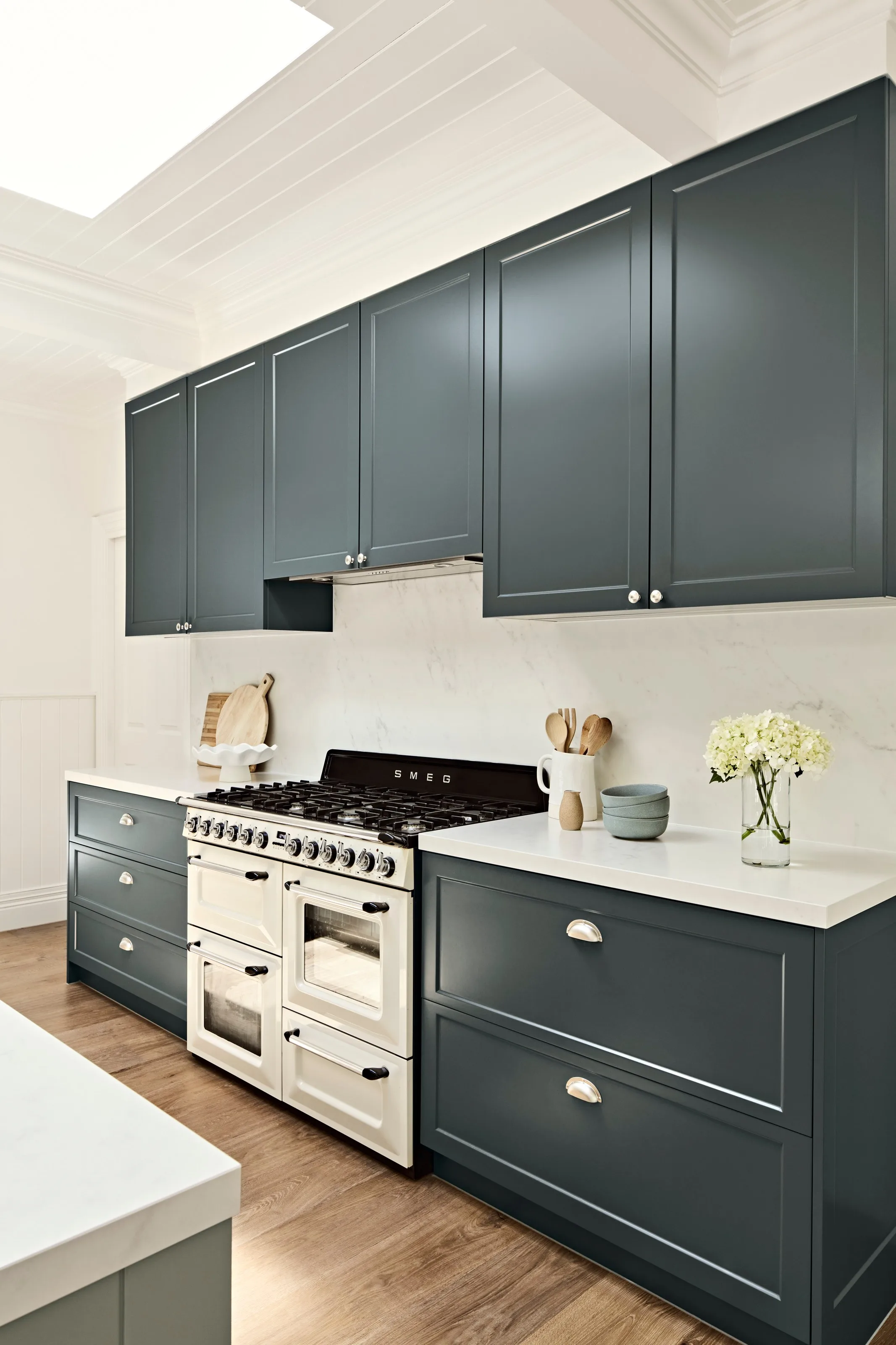 Cream freestanding range framed by charcoal shaker joinery and a marble-look splashback