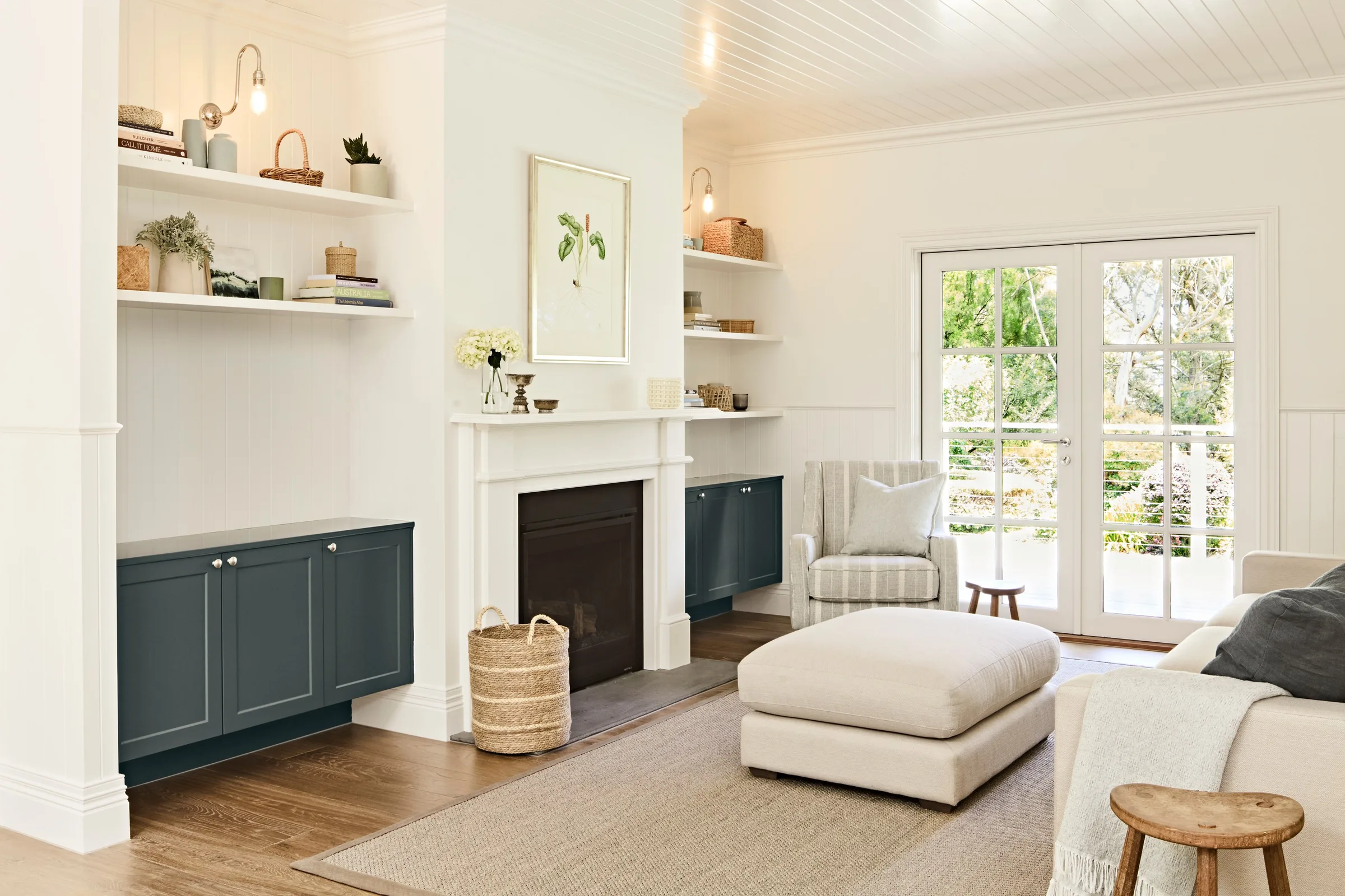 Living room fireplace flanked by dark green built-in joinery and open shelving
