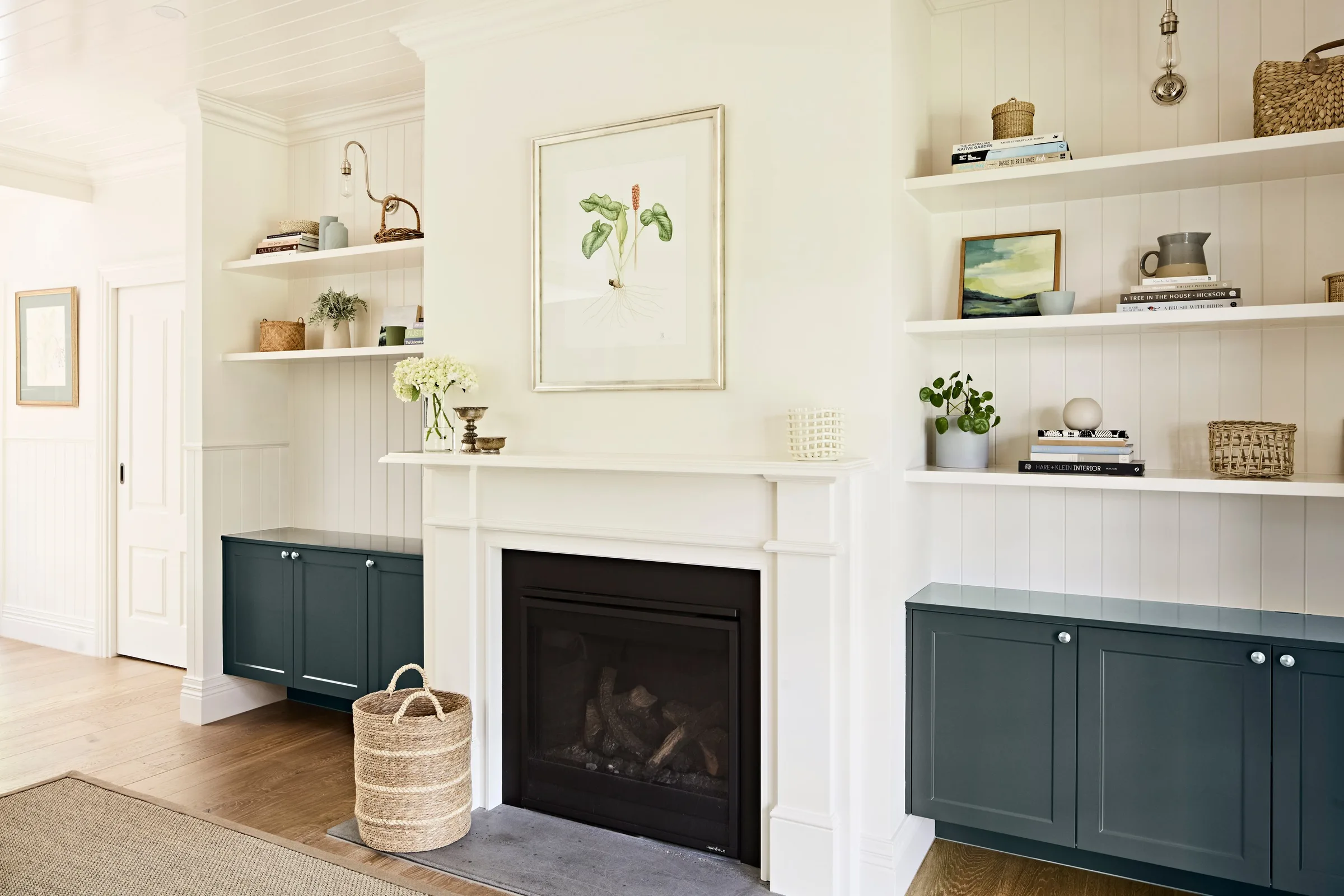 White timber mantel and black firebox centred between matching shelved alcoves