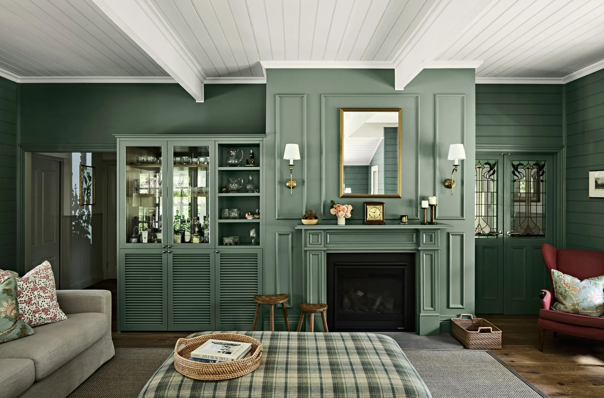 Glazed display cabinetry flanking the fireplace in the panelled green sitting room
