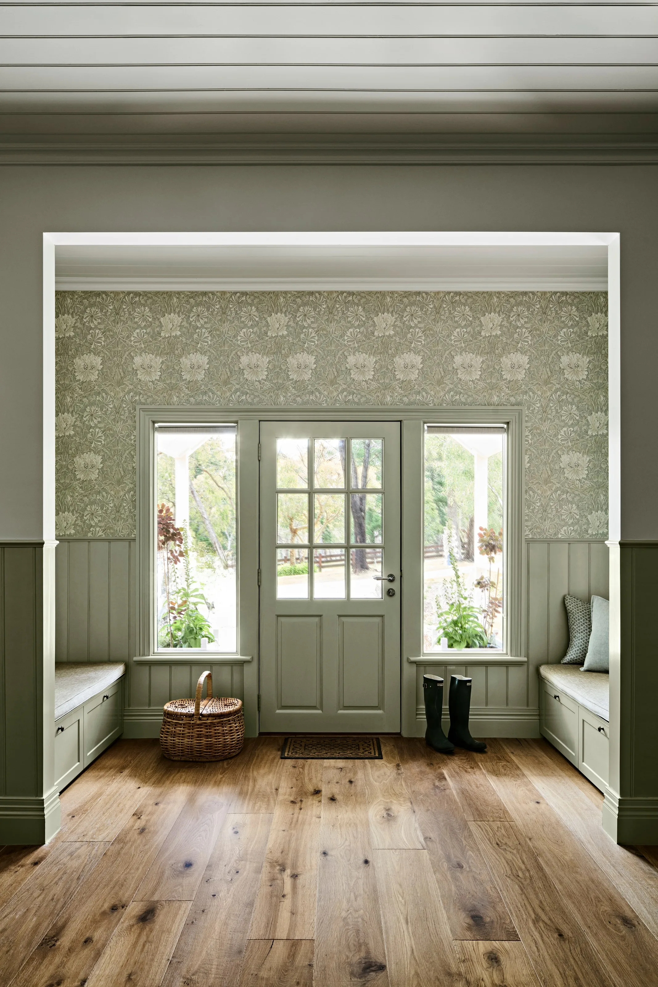 Front door with sidelights between built-in benches on wide oak boards