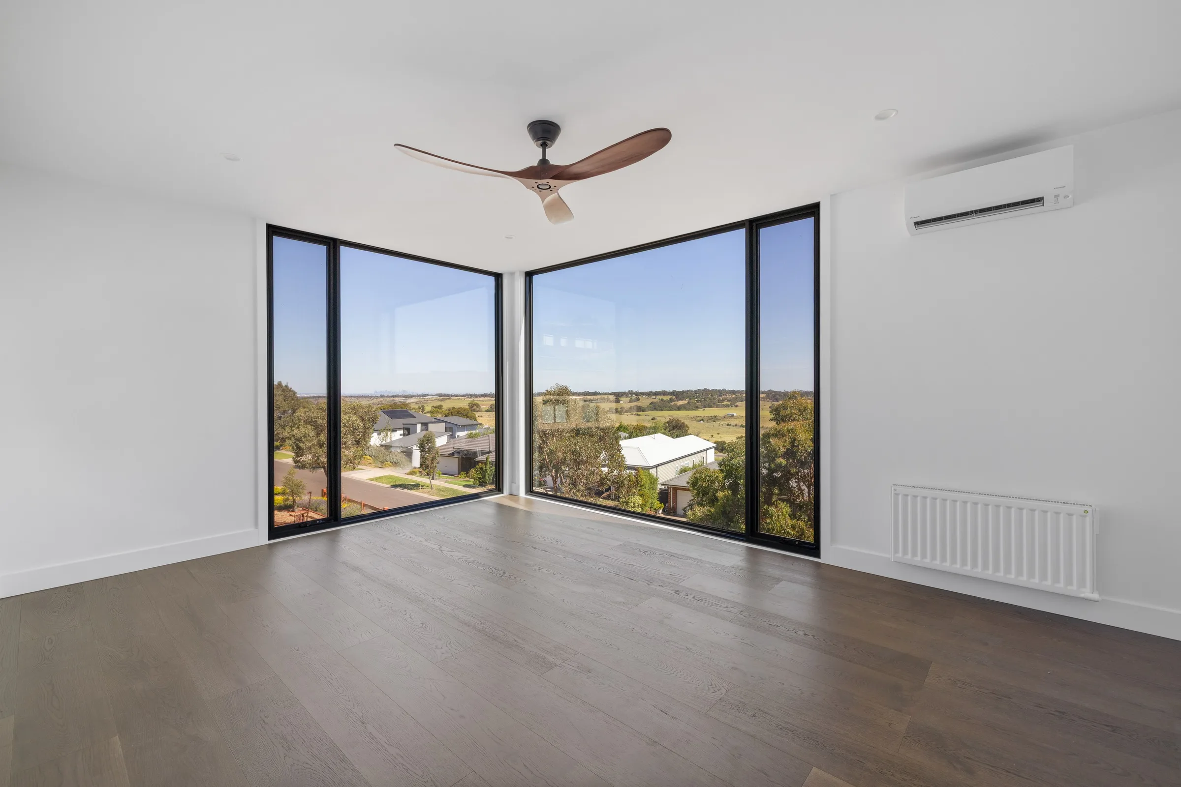 Empty upstairs room with corner glazing, timber ceiling fan and a rural outlook