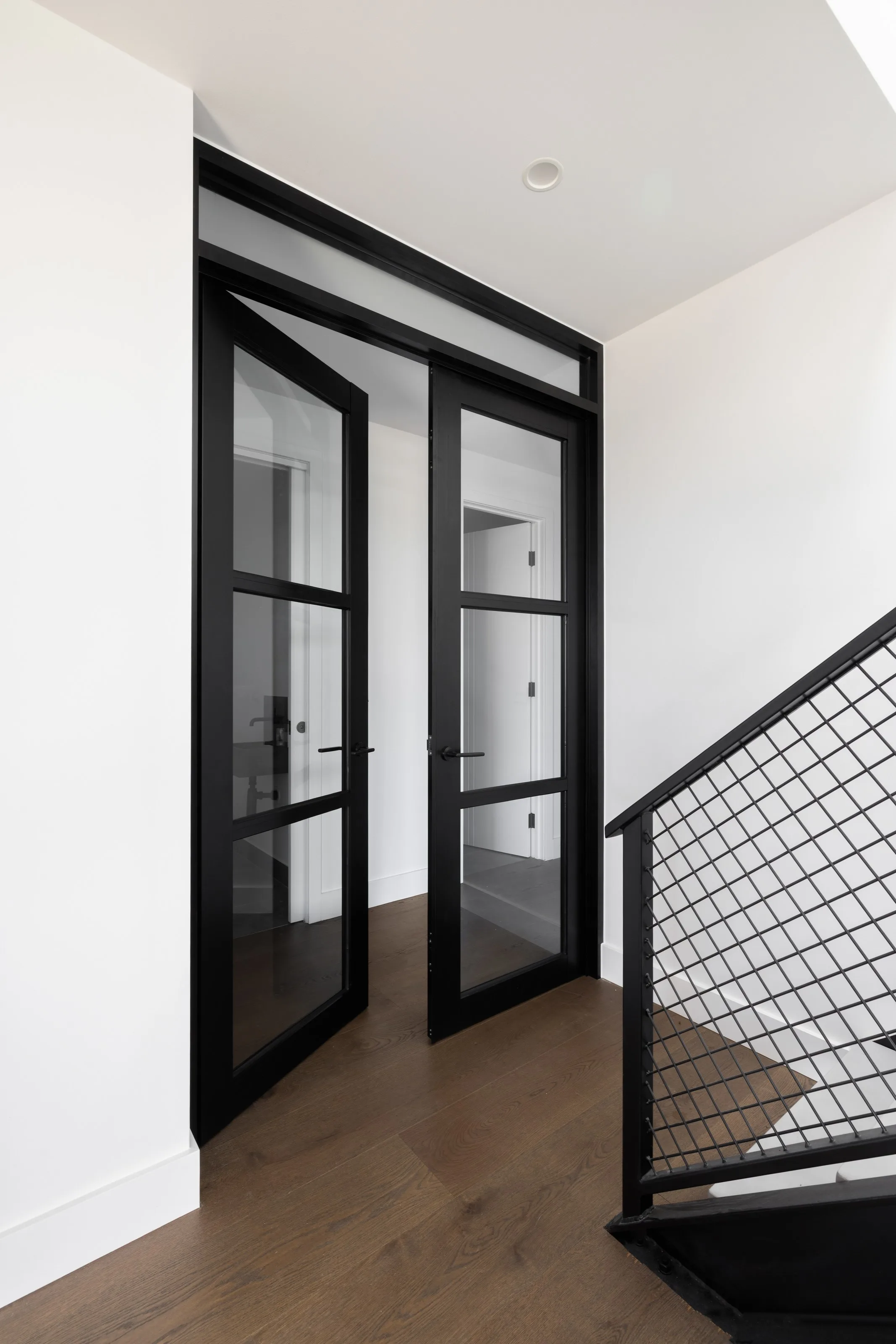 Black-framed glazed double doors off the landing, mesh balustrade alongside