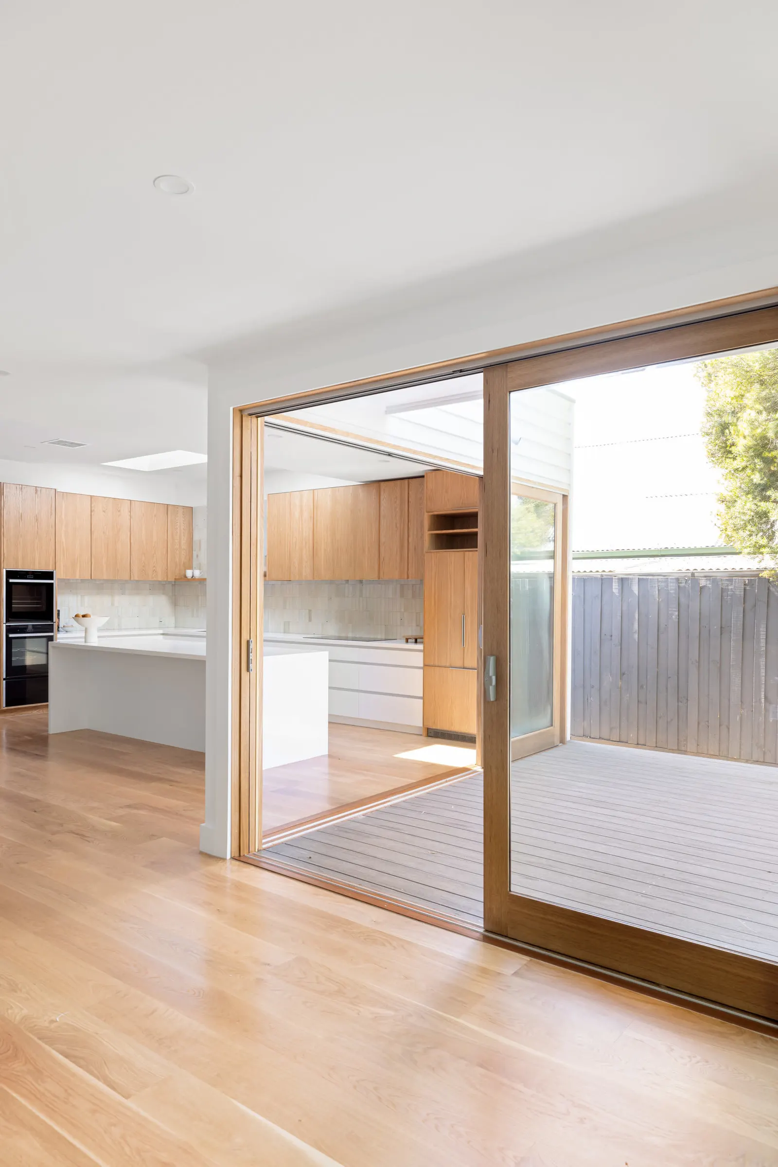 Timber-framed sliding door open from the living area onto the rear deck