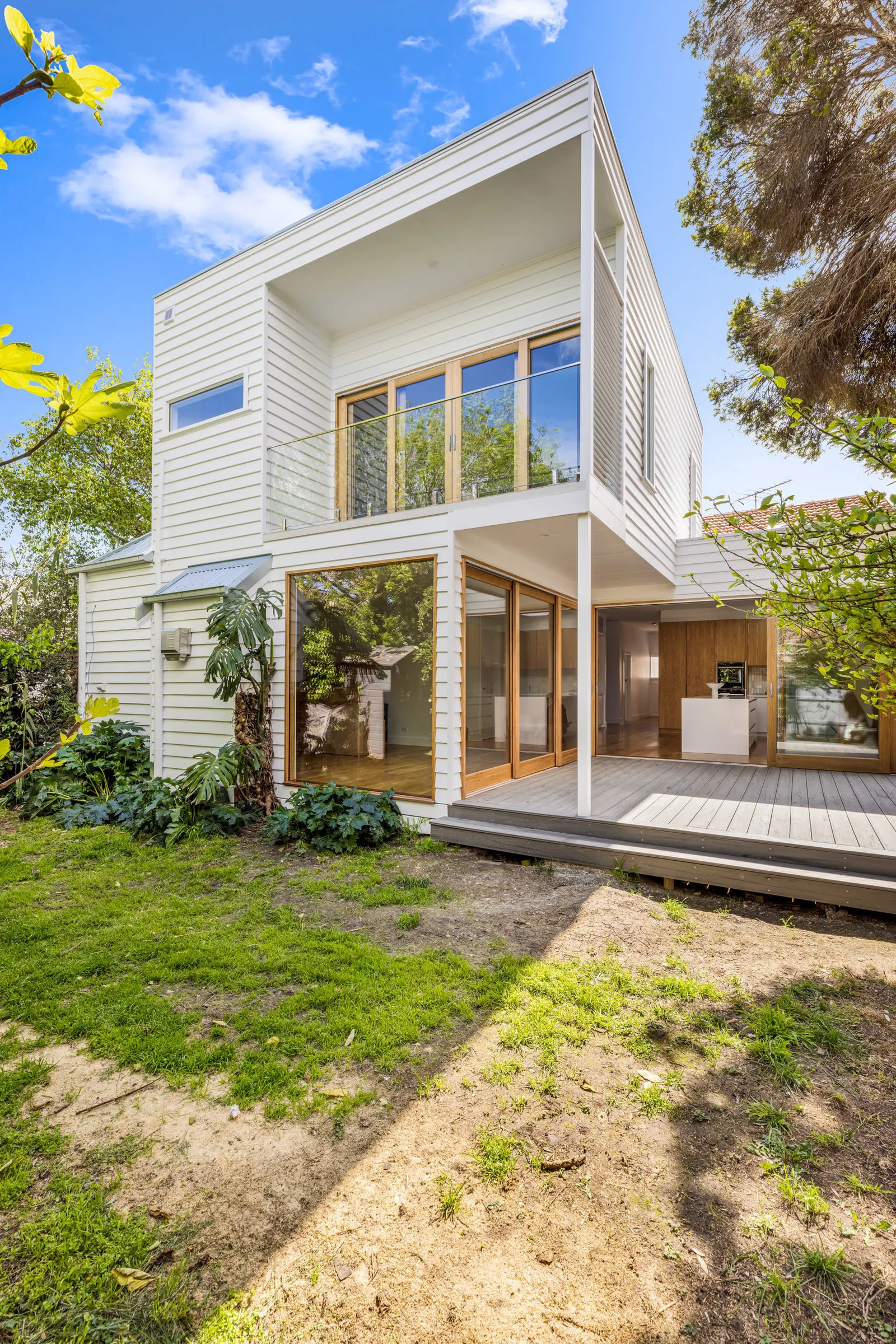Rear of the Williamstown renovation in white weatherboard, with a first floor balcony