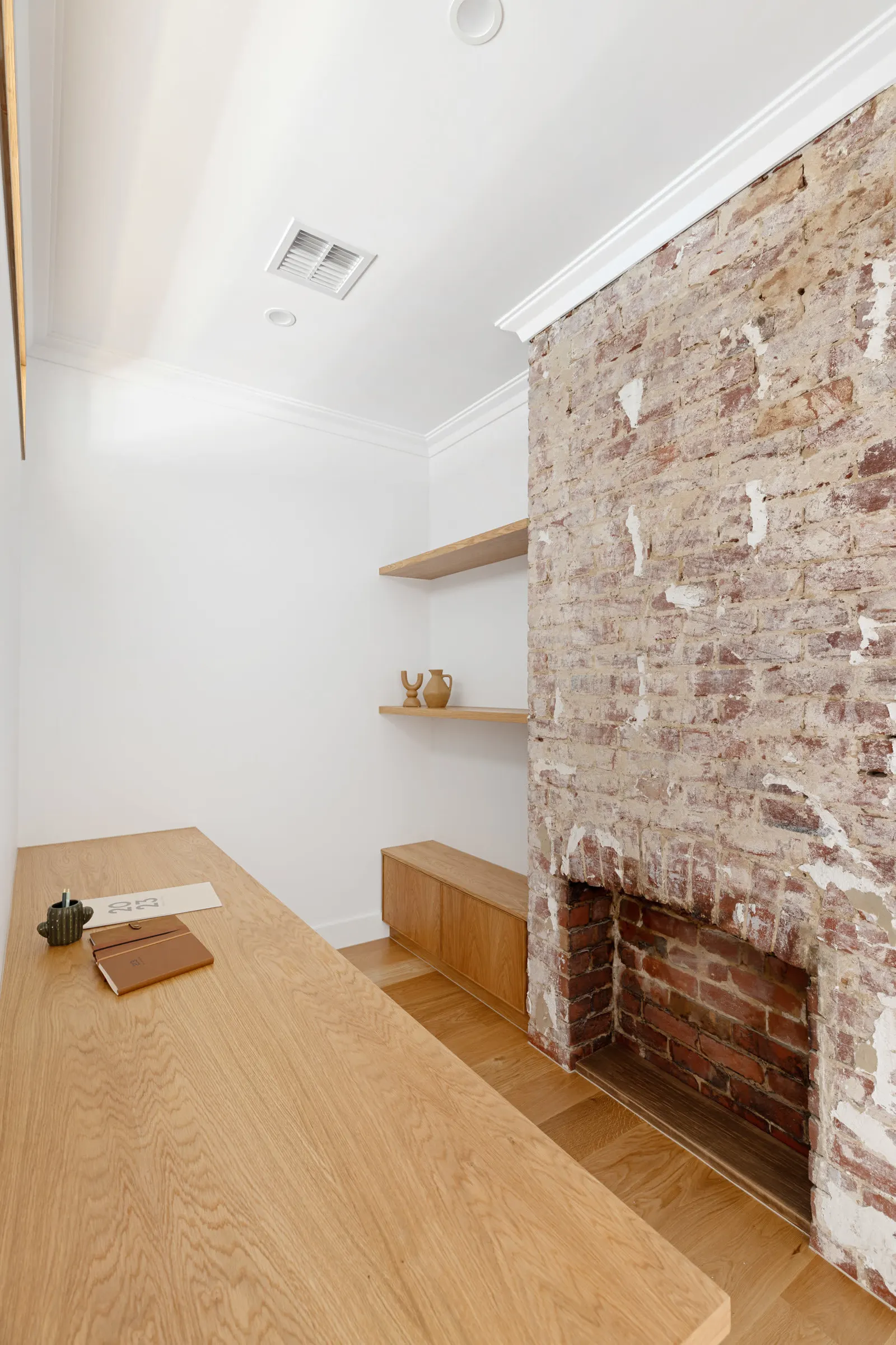 Study with a long oak desk beside an exposed original brick chimney breast