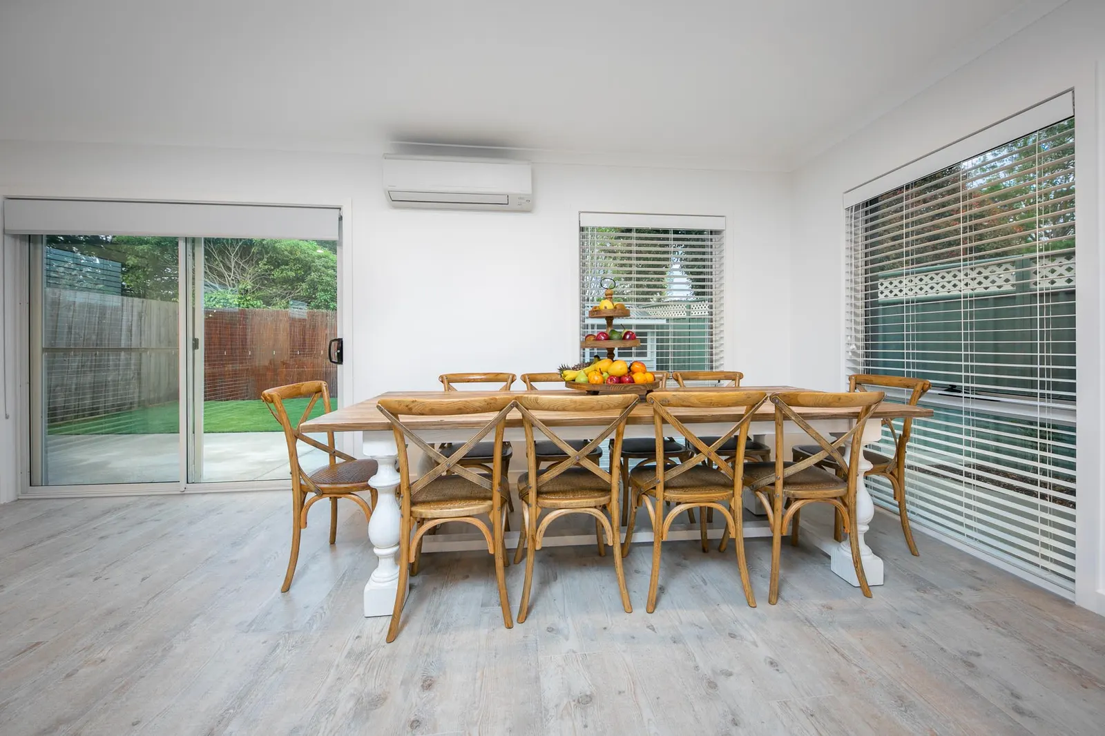 Dining area with a timber table and cross-back chairs beside sliding doors to the yard