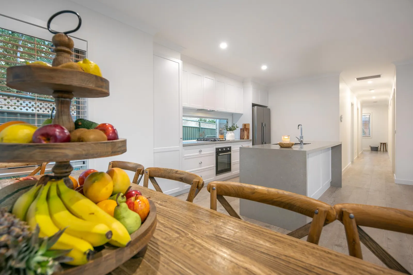 Open-plan view from the dining table across the kitchen island to the hallway beyond