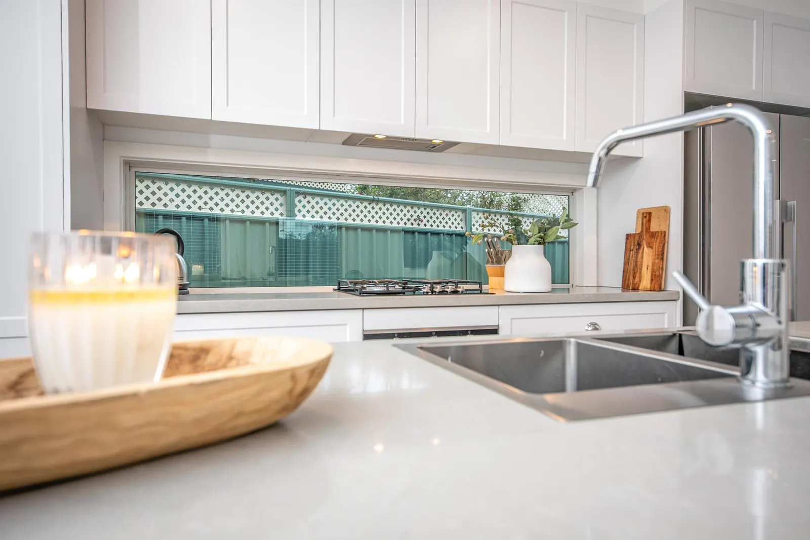 Benchtop detail with the undermount sink, chrome mixer tapware and gas cooktop behind