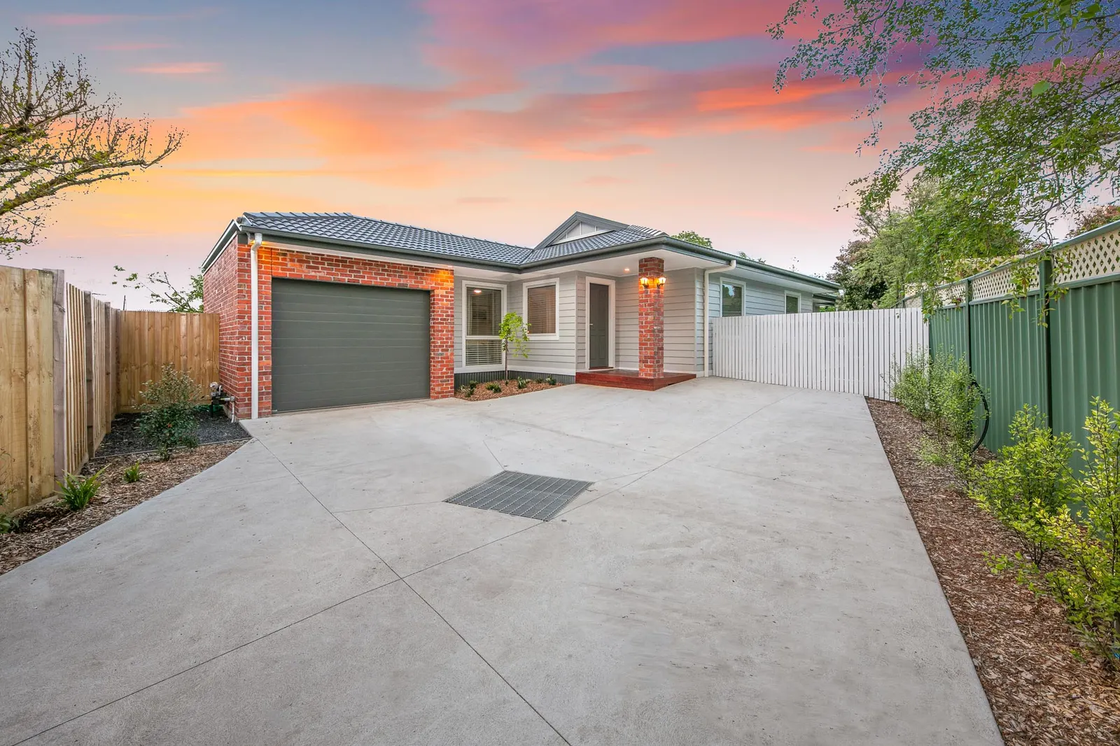 Twilight street view of the single-storey Worcester Rd home, wide concrete driveway to the garage