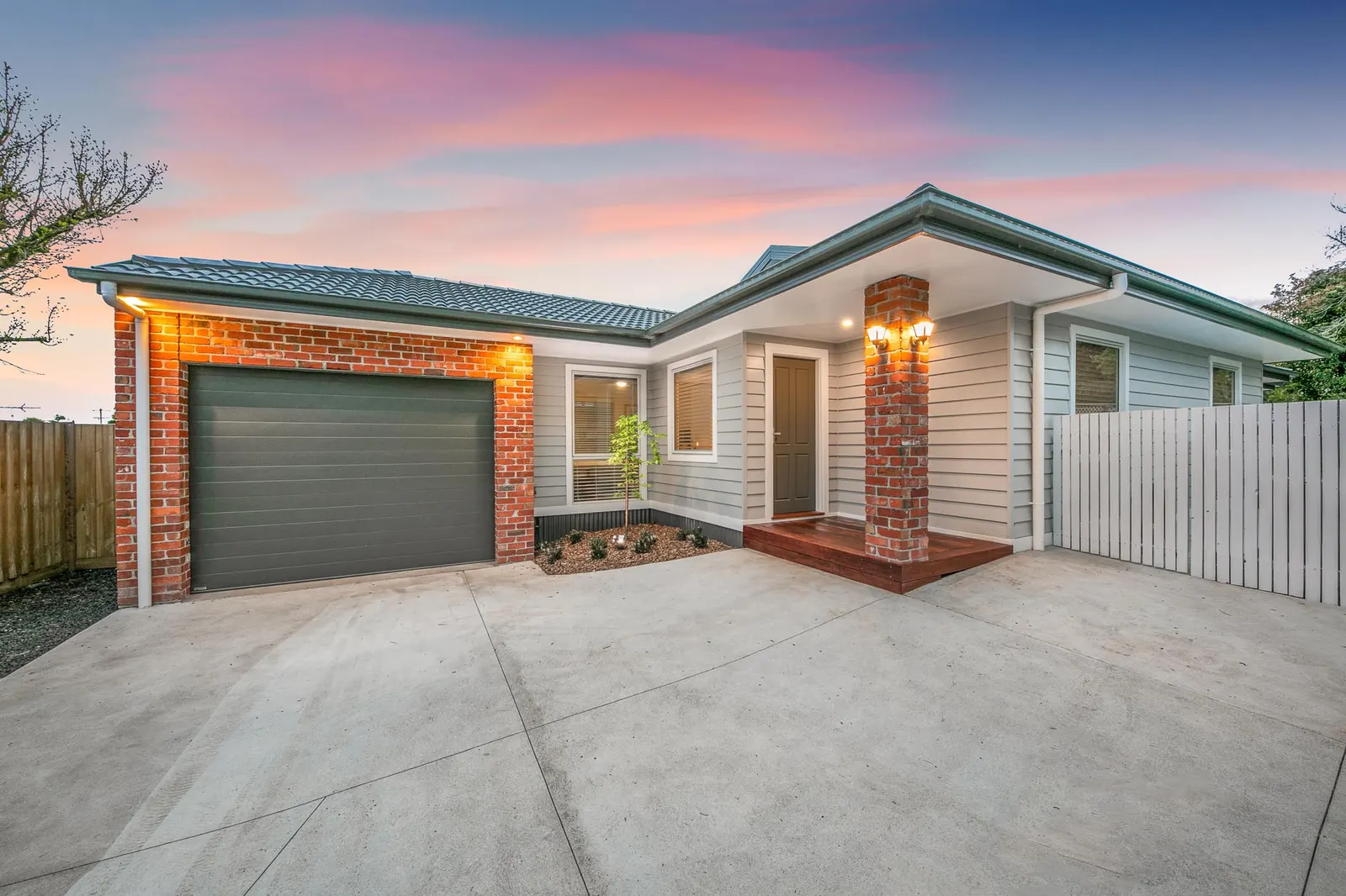Front elevation at dusk with brick and weatherboard cladding, sectional garage door and entry step