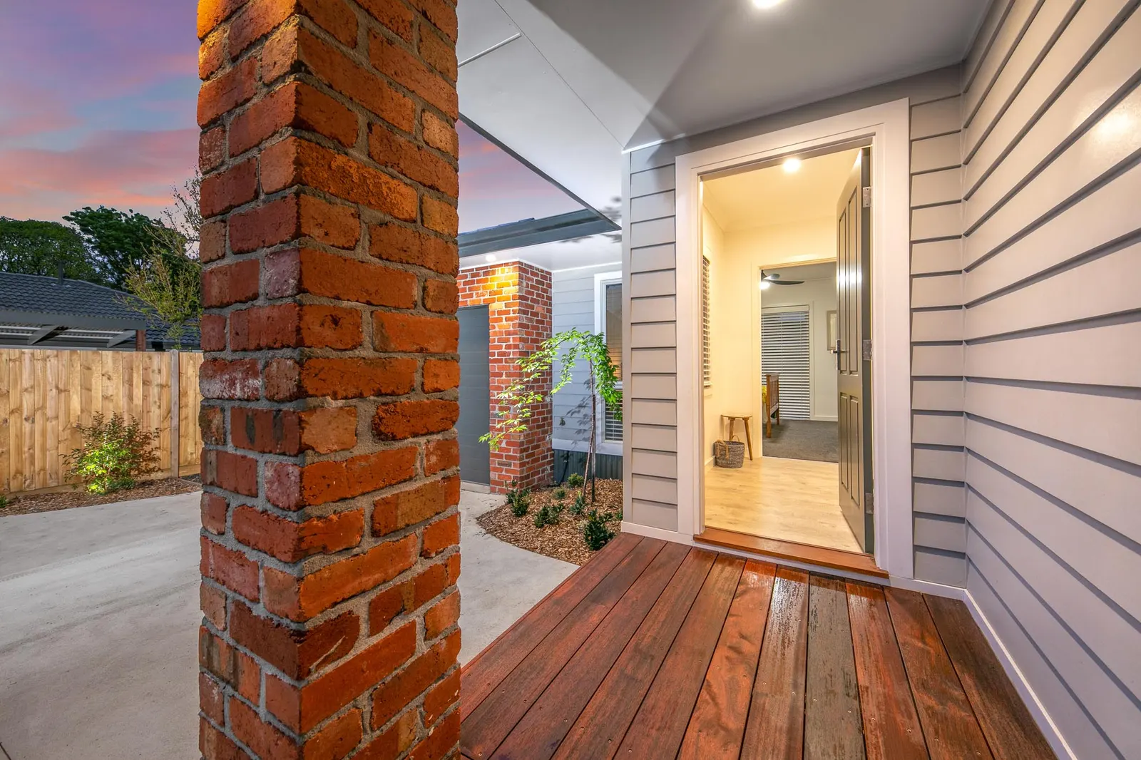 Recycled brick pier framing the timber entry deck, front door open to the hallway