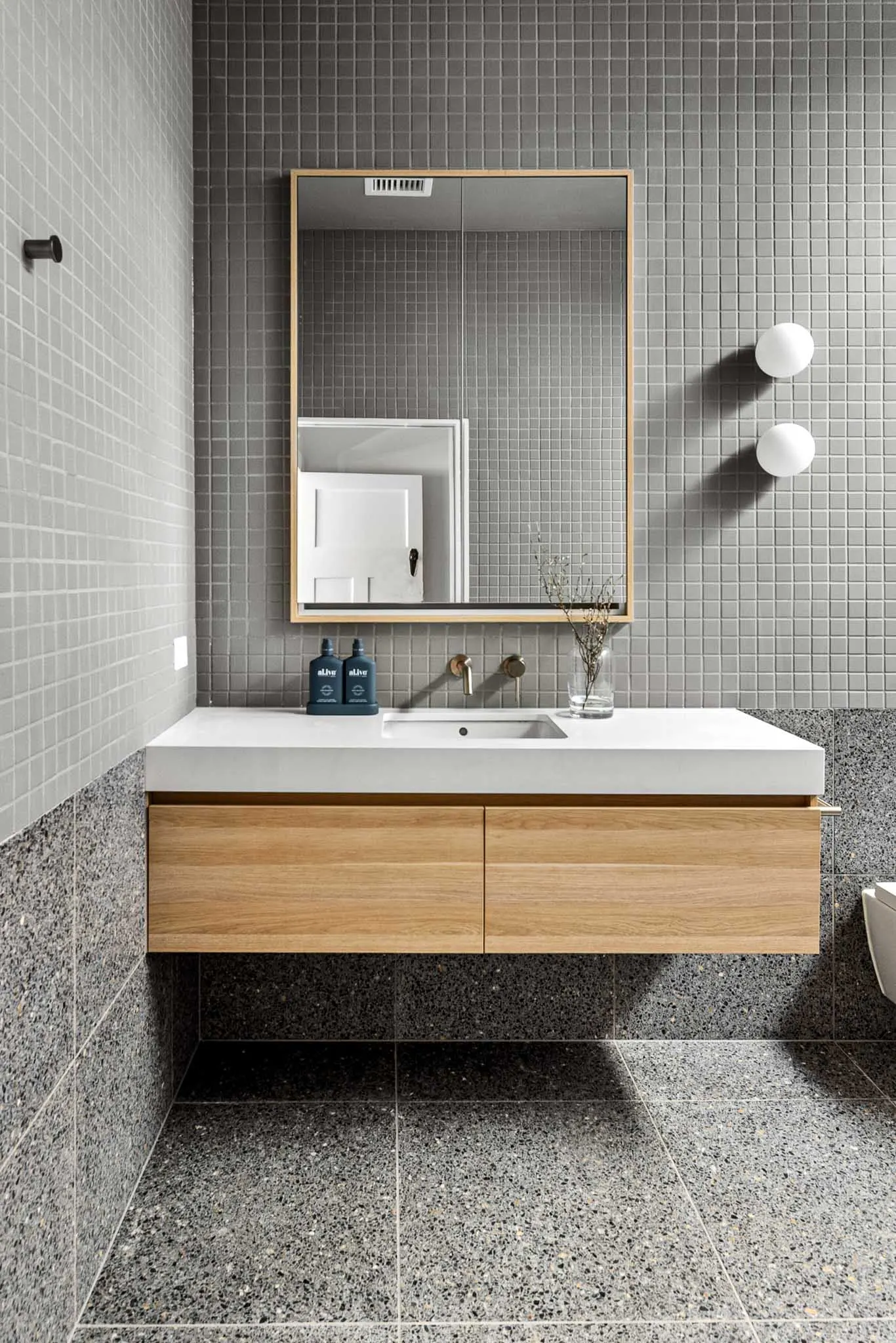 Floating oak vanity with white stone top, timber-framed mirror and brushed wall tapware