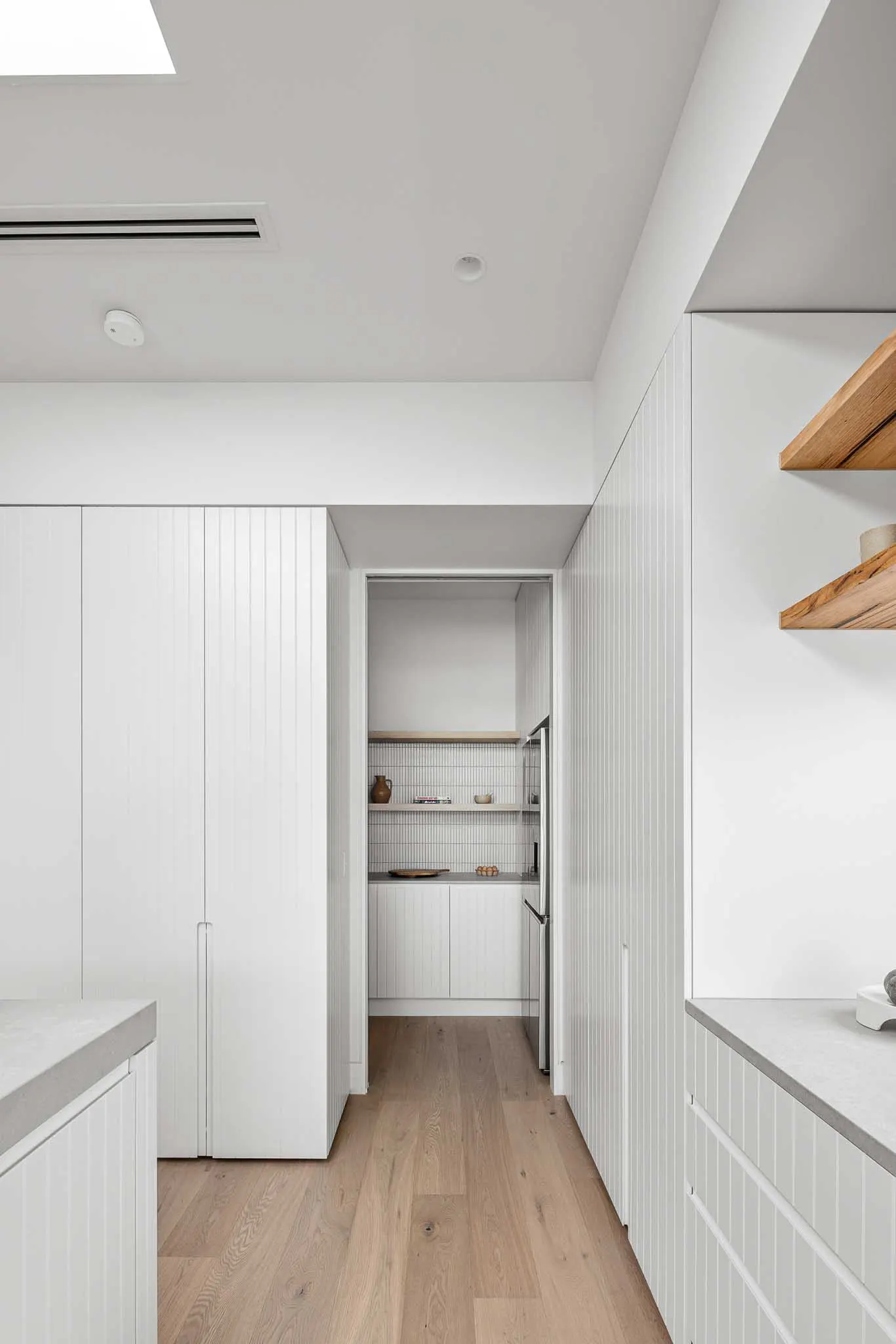 Tall white joinery framing the opening through to the butler&rsquo;s pantry, oak flooring