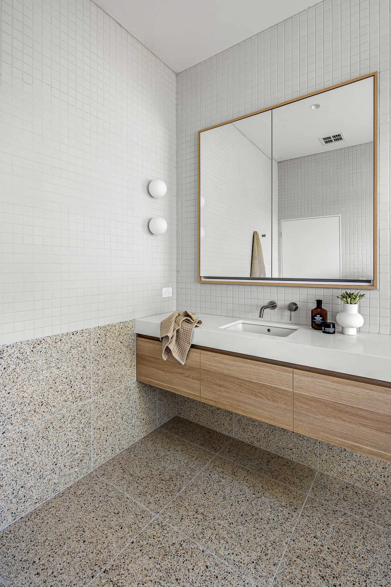 Vanity with oak drawers and stone top, wall-mounted tapware and opal wall lights