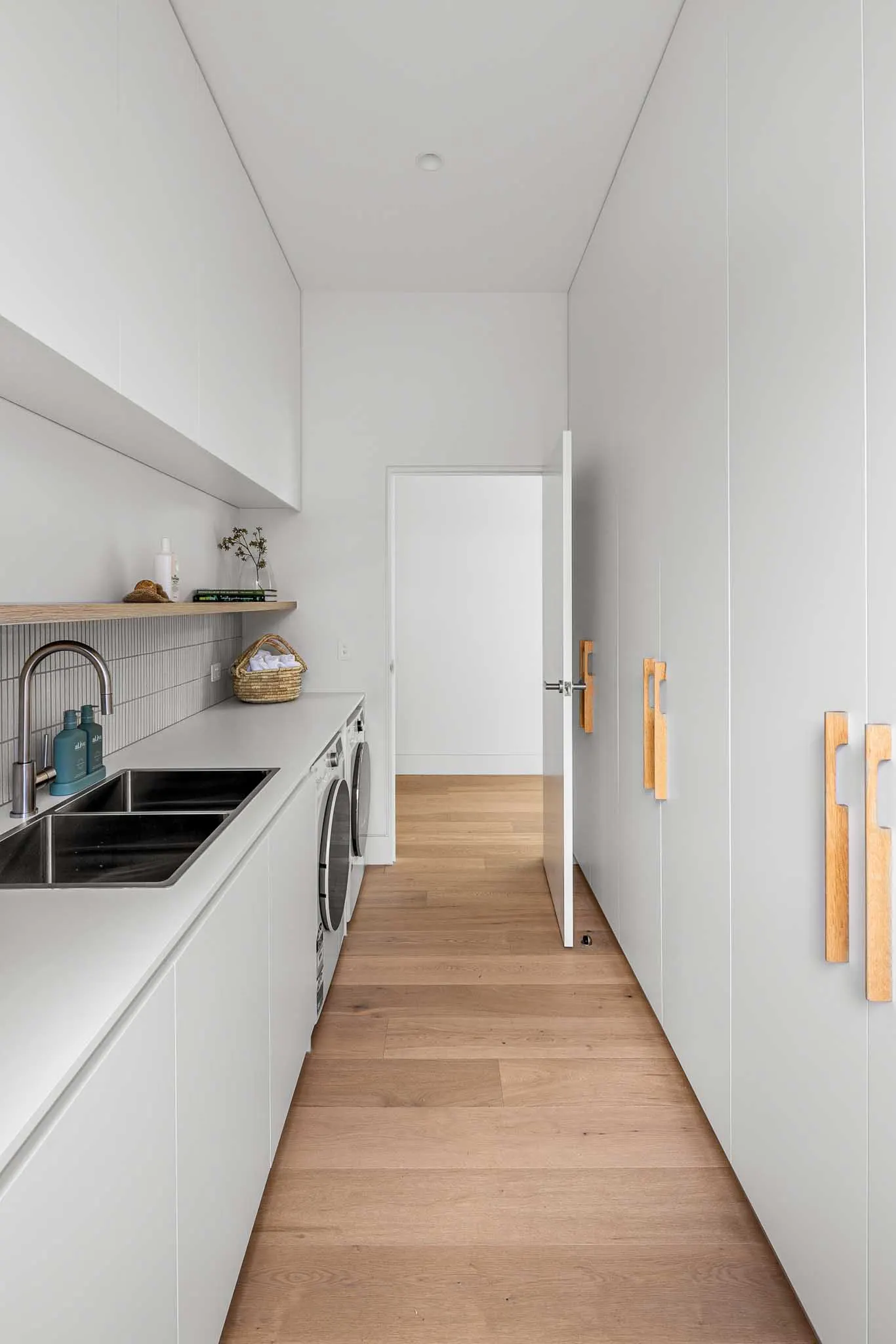 Laundry with double stainless sink, fluted tile splashback and slim timber cabinetry pulls