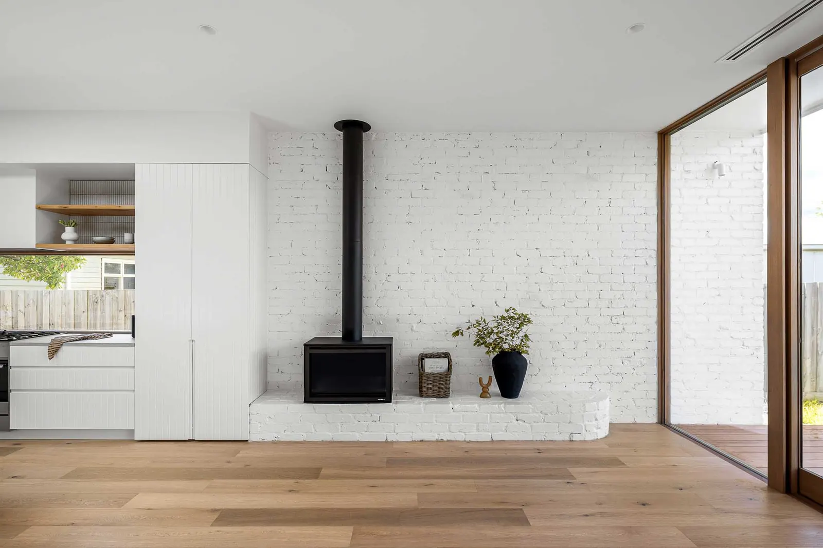 White painted brick chimney breast with black flue, raised hearth and wide oak boards