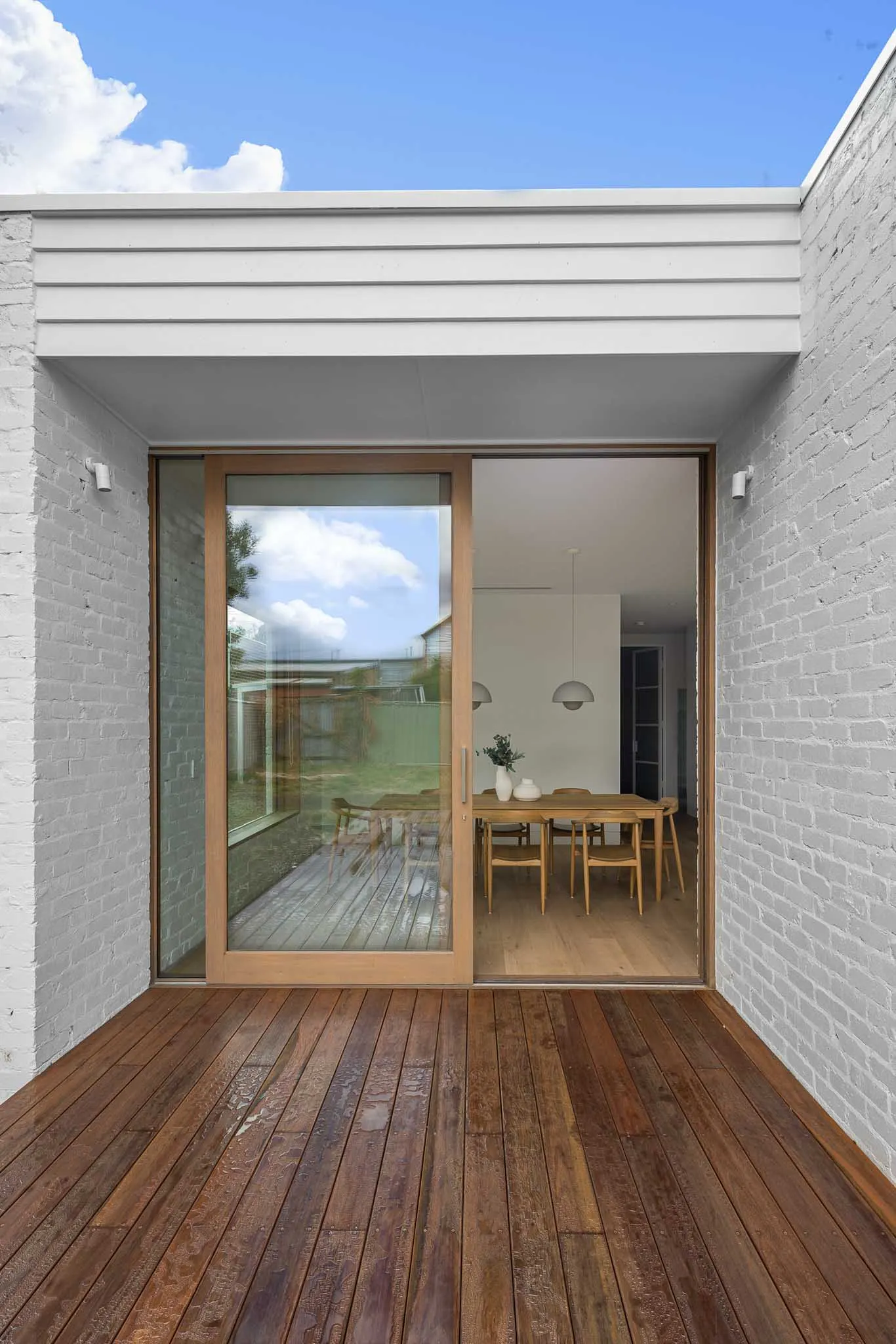 Decked courtyard at Yaldwyn St, Kyneton, white painted brick walls and a sliding timber-framed door